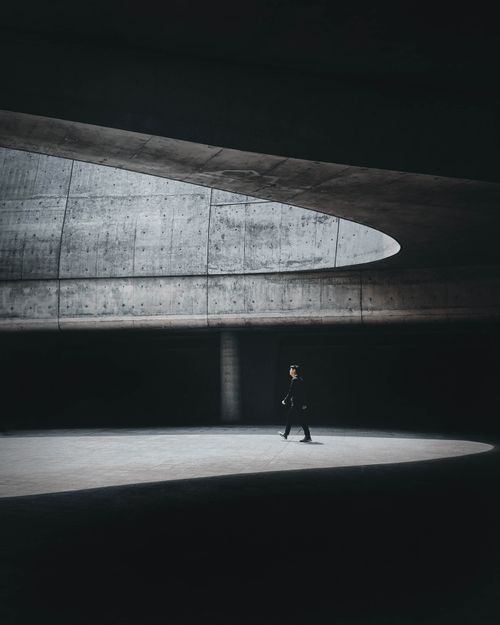 Free Man walks in sunlight within a modern, concrete architectural structure in Seoul. Stock Photo