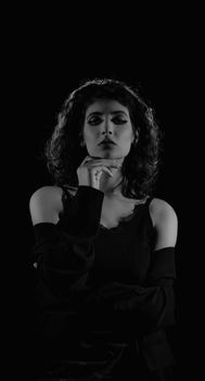Graceful black and white portrait of a Middle Eastern woman in a studio setting with a contemplative pose.