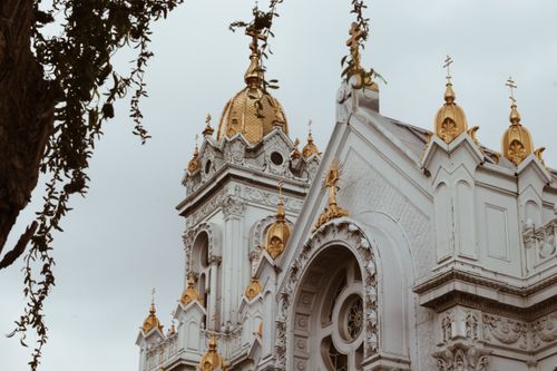 Free High angle view of a detailed ornate orthodox church facade with golden domes against a cloudy sky. Stock Photo