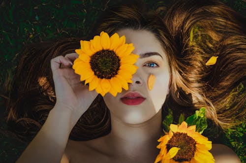 Woman with Sunflower Lying on Grass