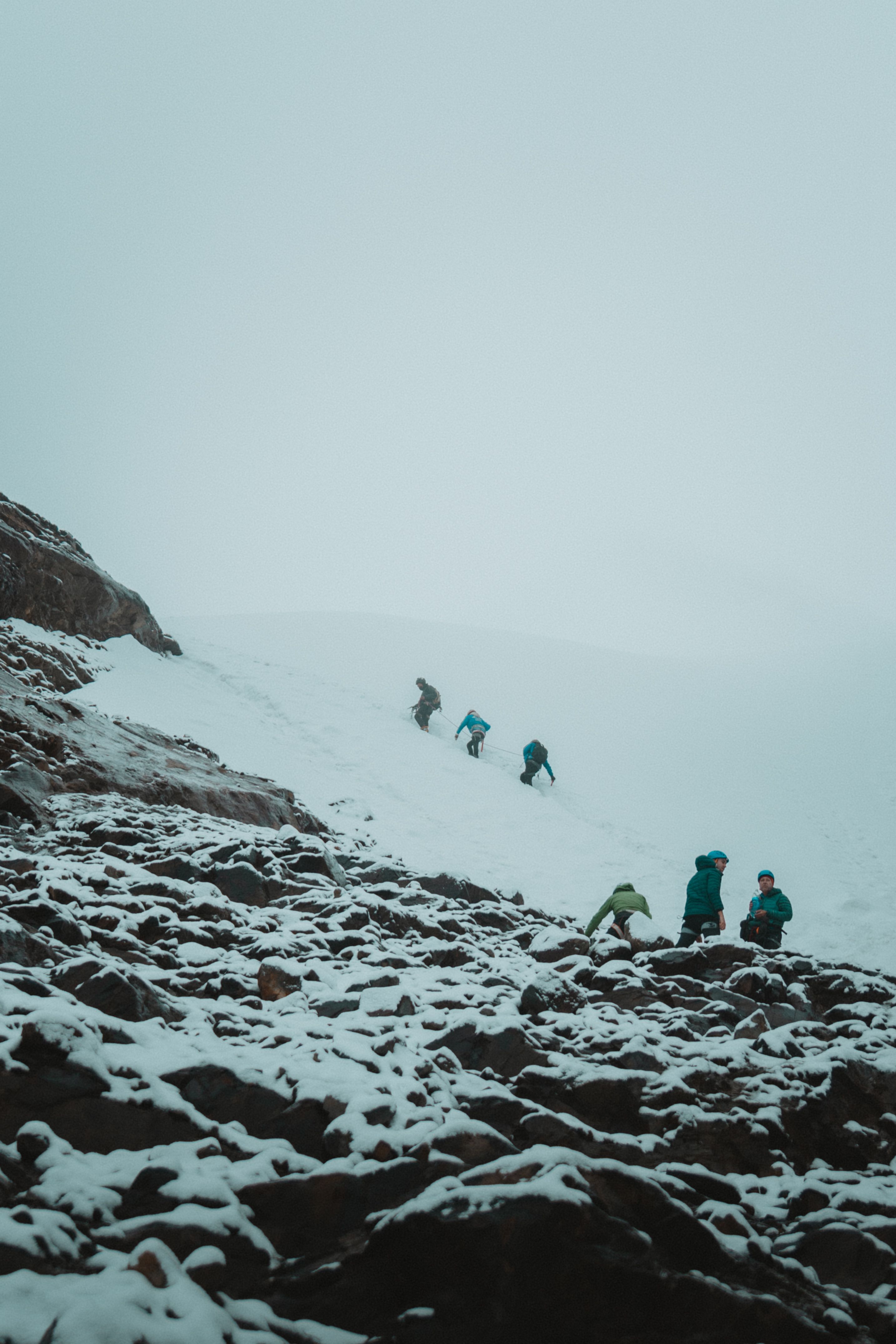 Adventurers climbing snow-covered rocks in the Andes mountains during winter
