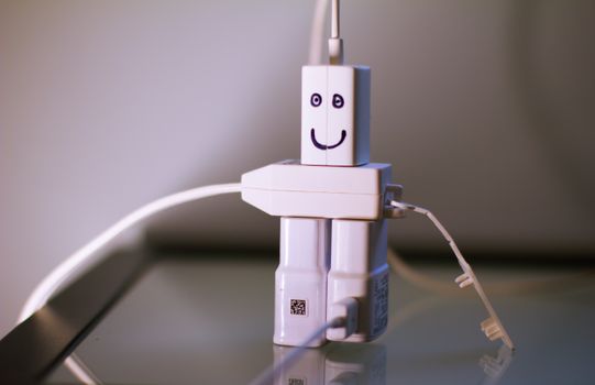 A unique robot-like figure crafted from phone chargers with a smiling face.