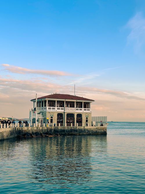 Free Historic pier building in Istanbul reflecting on the sea during a serene sunset. Stock Photo