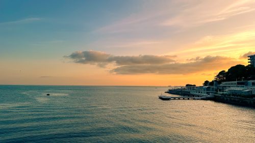 Free A mesmerizing sunset over the calm sea with a picturesque coastal village in view. Stock Photo