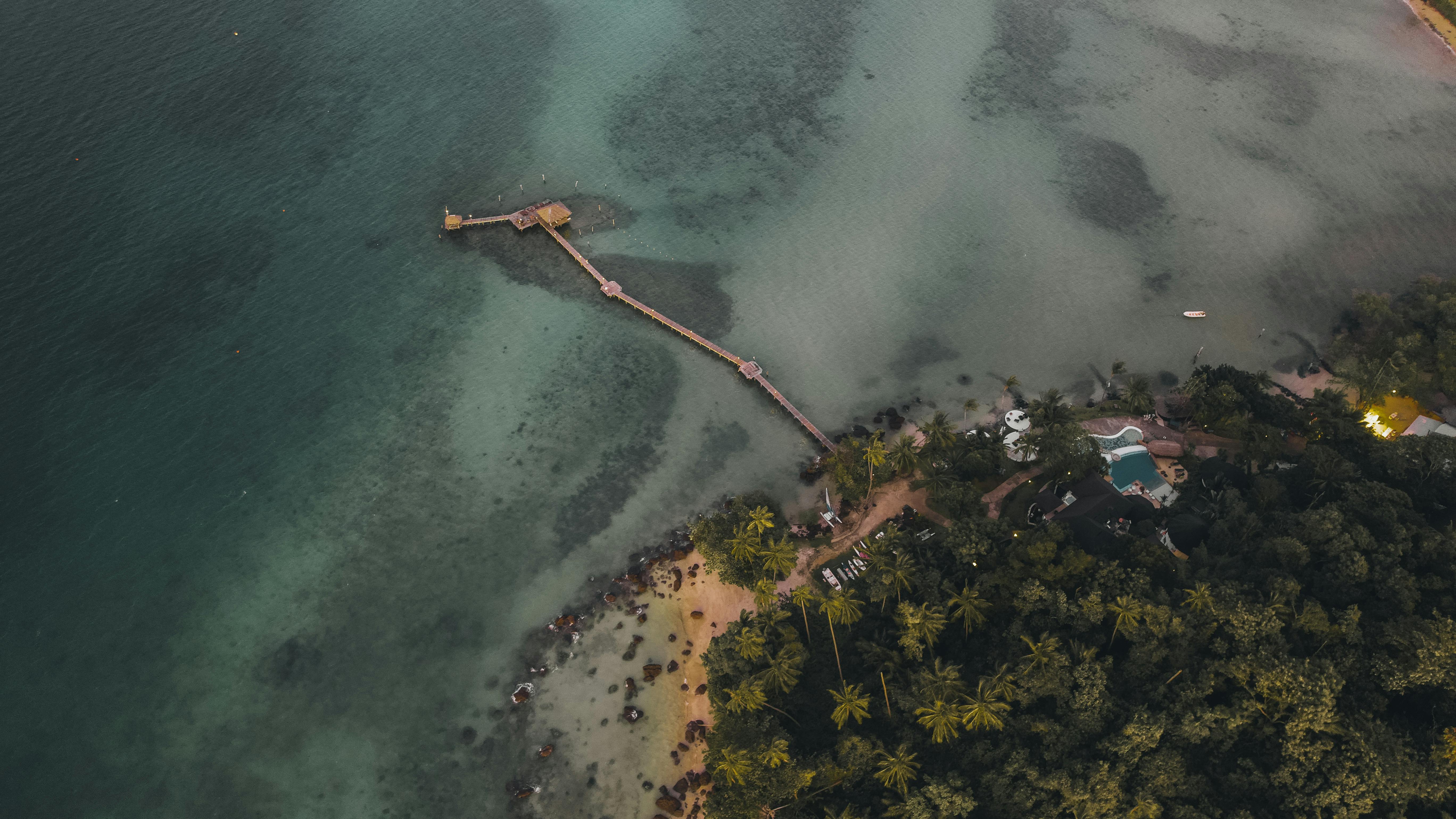 Stunning aerial view of Ko Mak's pier and beach with lush palms in Trat, Thailand.
