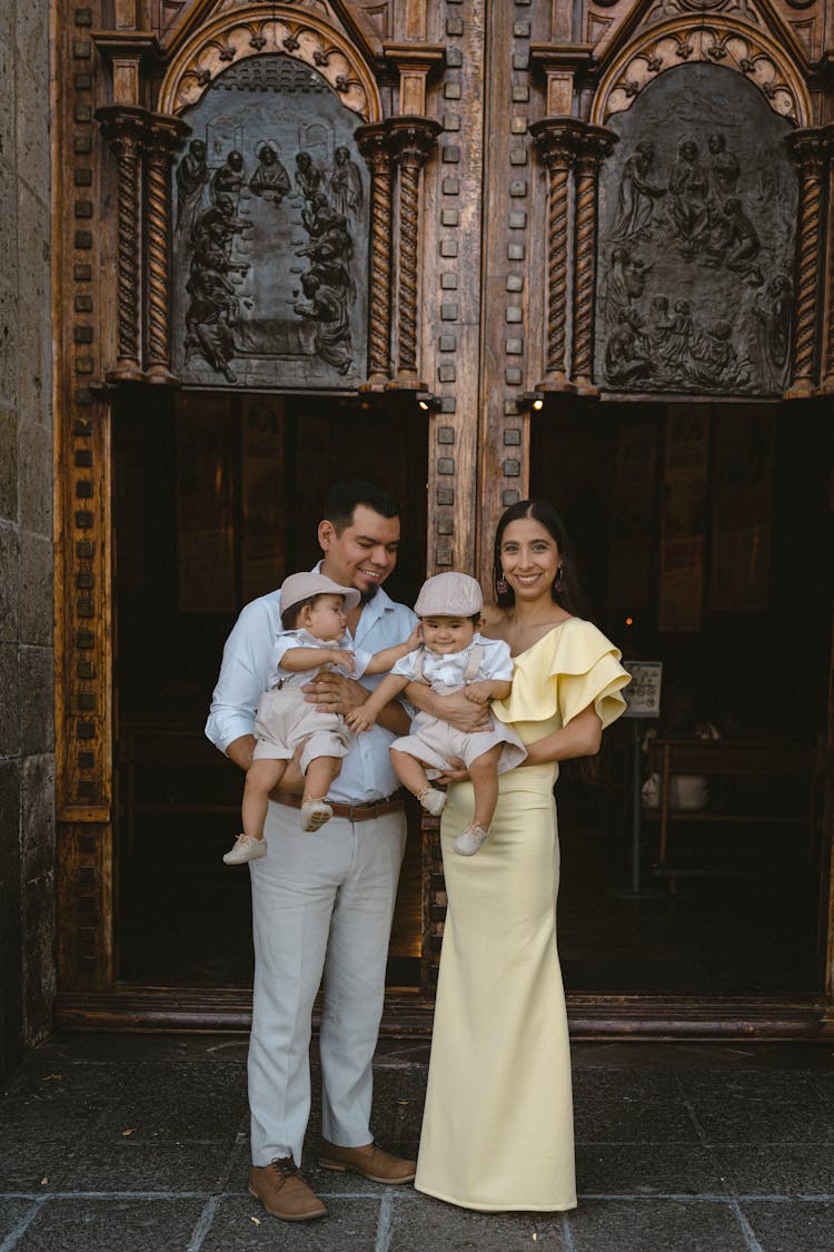 Father And Mother Posing With Babies In Church Entrance