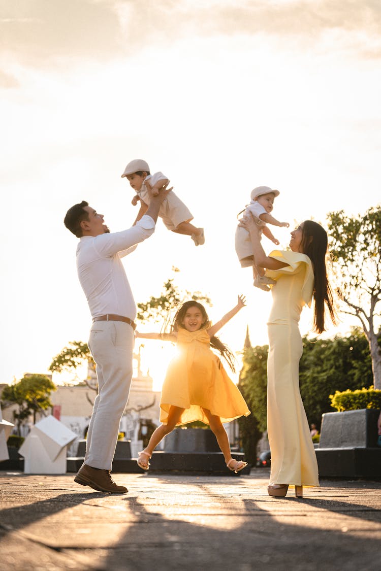 Mother And Father Raising Babies Up With Daughter Jumping Between