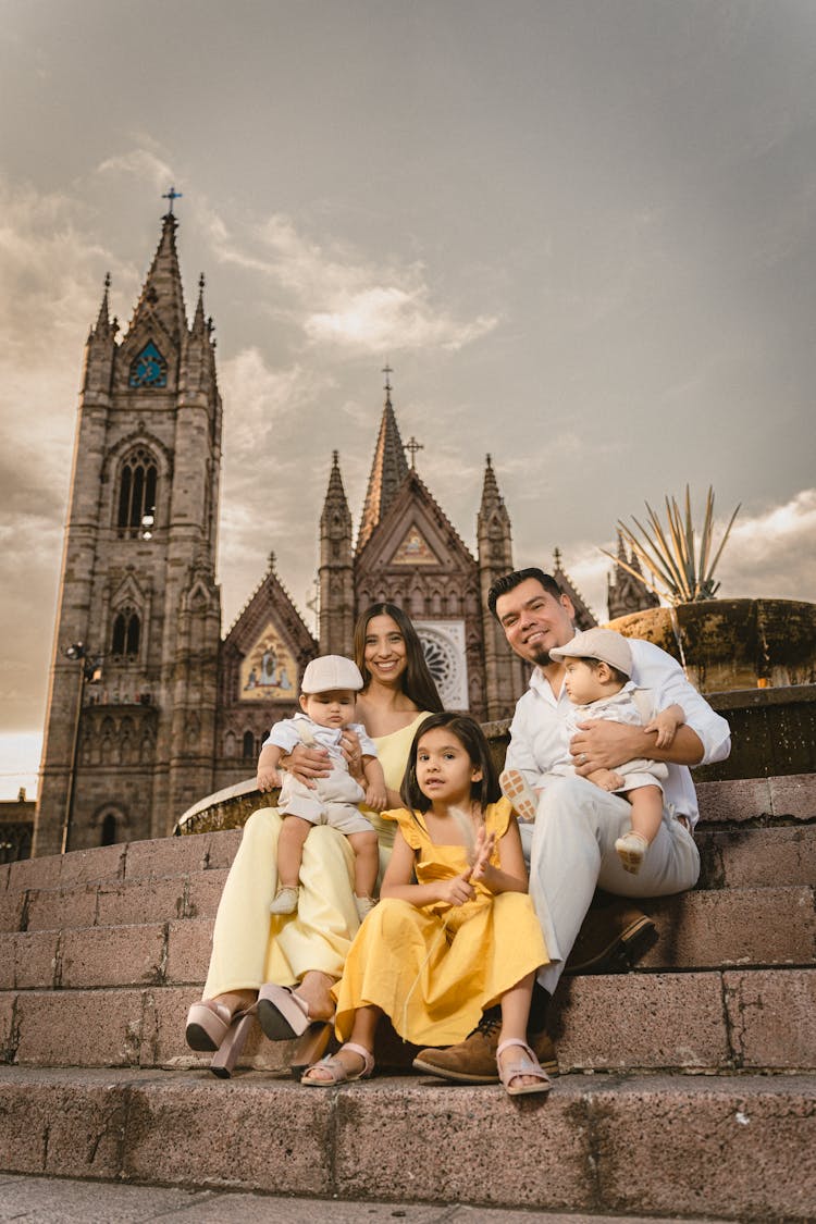 Family With Children Sitting On Steps In Front Of Templo Expiatorio Del Santísimo Sacramento In Mexico 