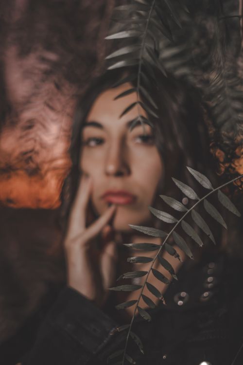 Free An artistic portrait of a woman with a fern overlay, captured at sunset for a moody and dramatic effect. Stock Photo