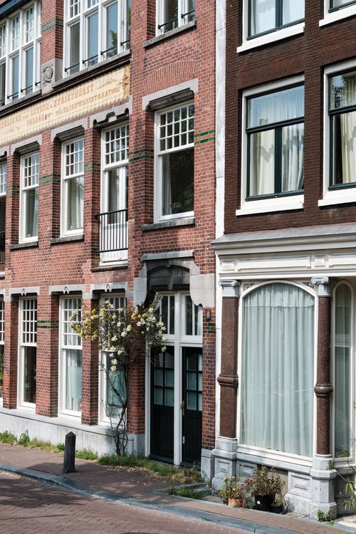 Free Classic brick houses with floral details along an Amsterdam canal, showcasing urban heritage. Stock Photo