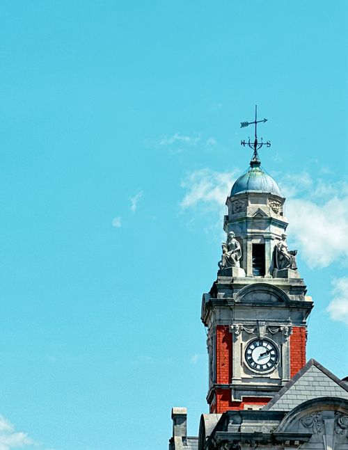 Free A historic clock tower stands prominently against a vibrant blue sky, showcasing its architectural details. Stock Photo
