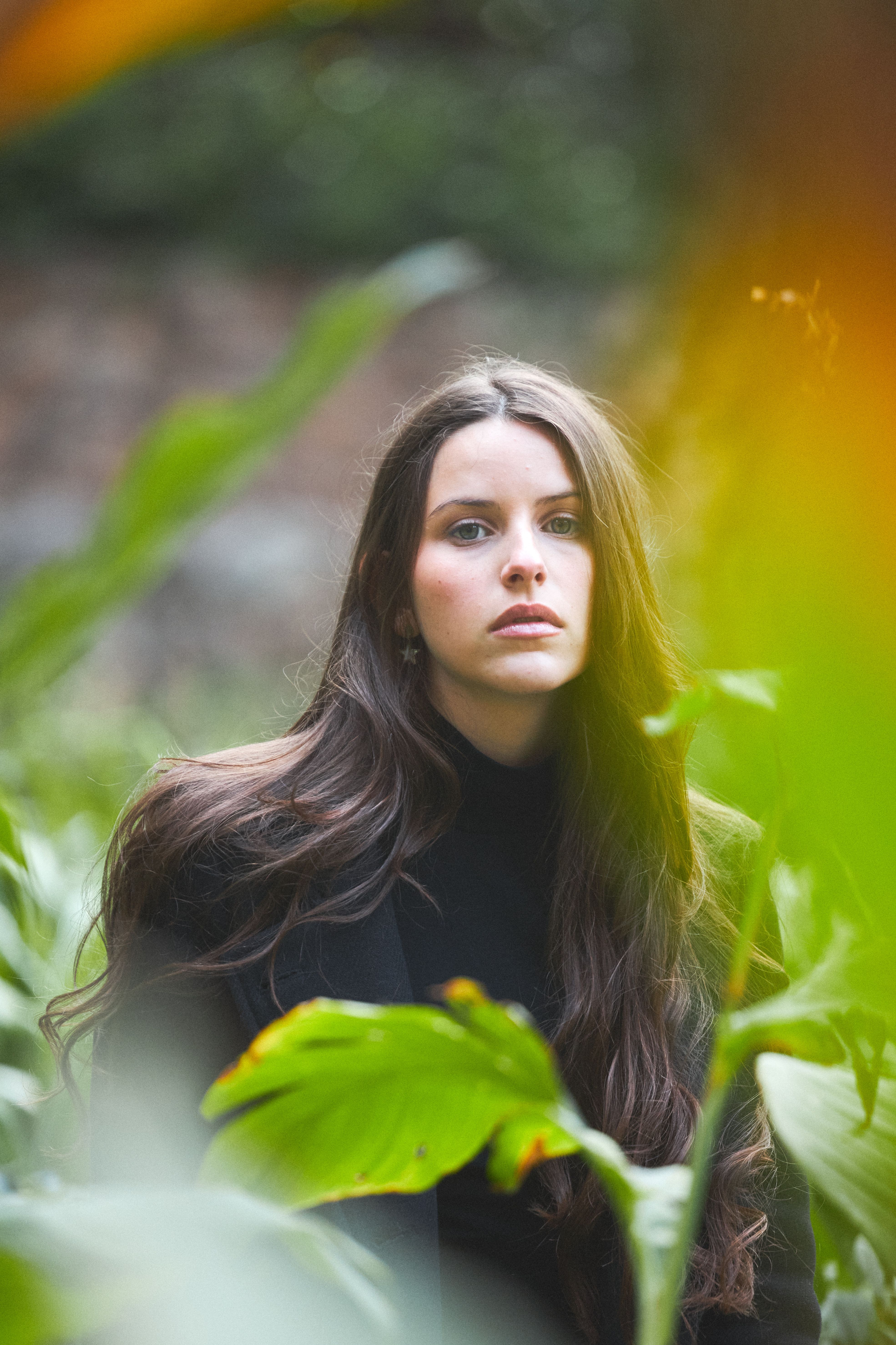 A woman in a black coat is standing in a field of plants · Free Stock Photo