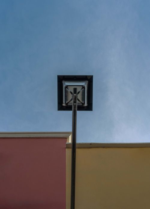 Free Creative upward view of urban lamp post against the sky with colorful walls. Stock Photo