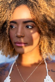 Close-up portrait of a woman with curly hair, highlighting natural beauty and shadows.