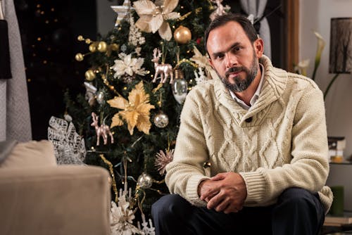 Man in White Warm Sweater Sitting by Christmas Tree