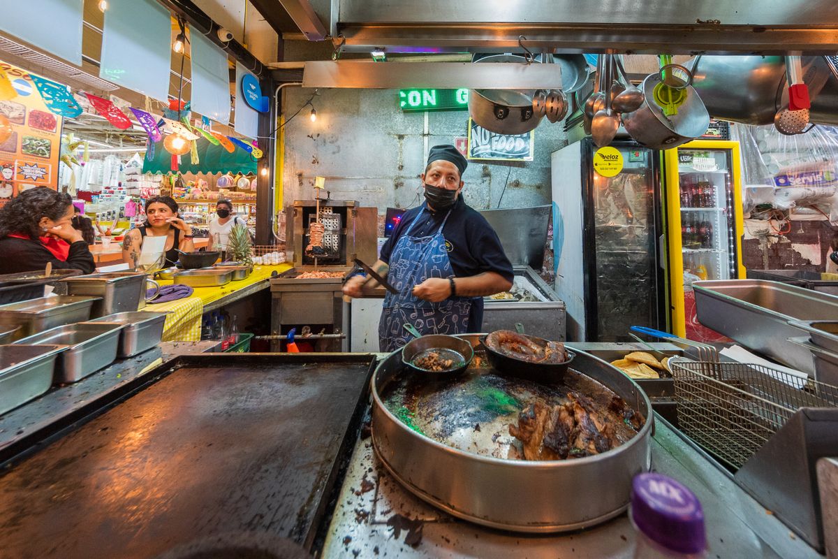Puesto de comida callejera mexicana con tacos y antojitos coloridos en un mercado local
