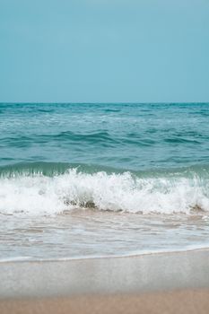 Peaceful ocean waves gently lapping the sandy shore under a clear blue sky.