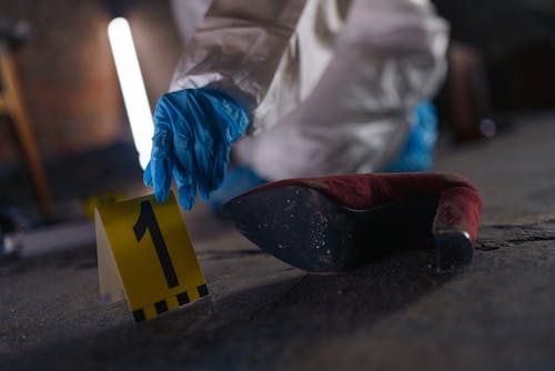 Hand Putting Evidence Number on Pavement on Crime Scene
