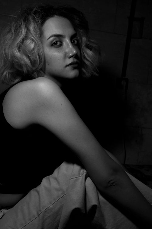Free Moody black and white portrait of a woman with short blonde hair sitting and posing. Stock Photo