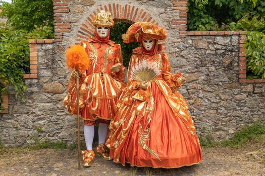 Couple in distinctively ornate Venetian costumes posing at a festival in Clisson, France.