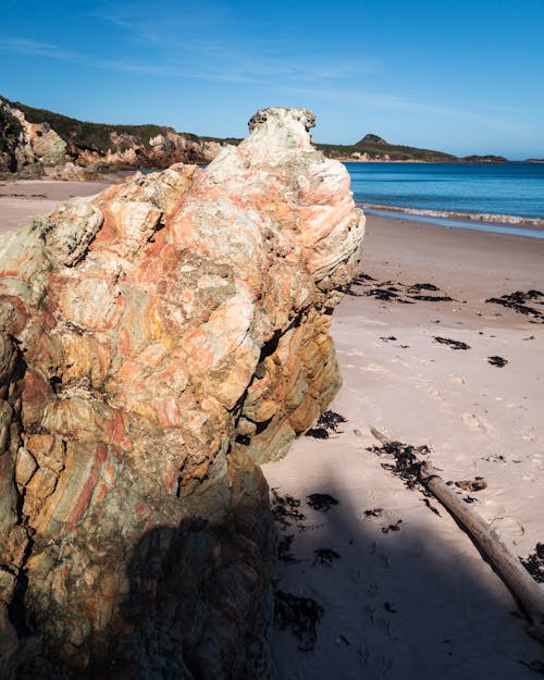 View of a Boulder on a Beach with Cliffs in the Background 