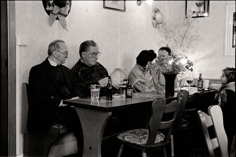 People Sitting By Table With Priest