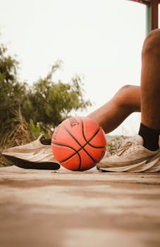 Close-up of basketball player's legs with ball outdoors on a court.