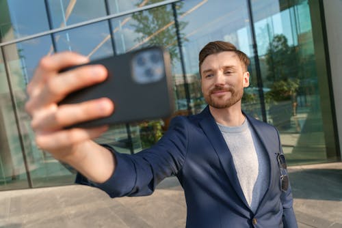 Elegant Man Taking a Selfie in front of a Modern Building 