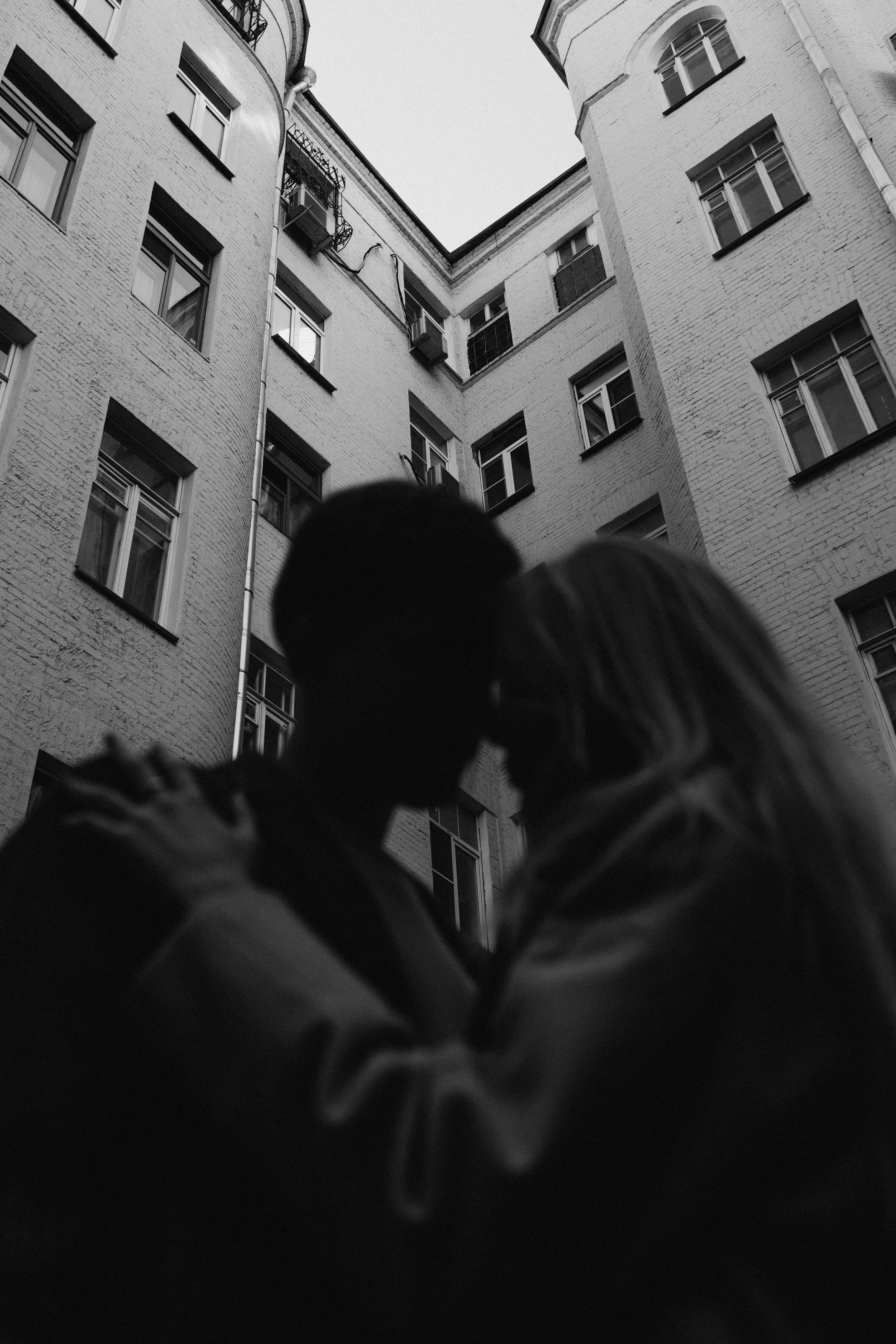 Silhouette of a couple embracing in an apartment courtyard, conveying romance and intimacy.