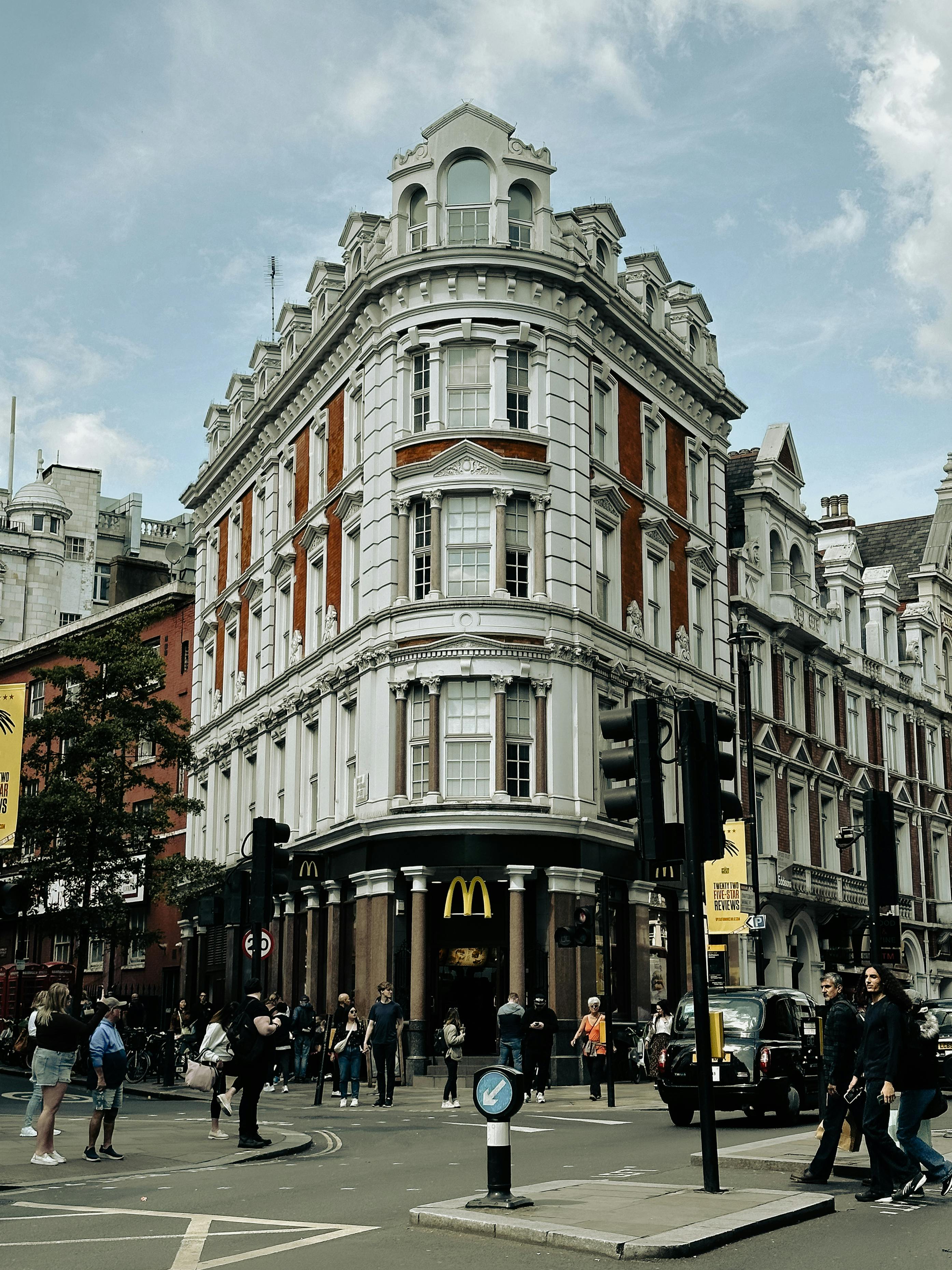 Free Street view of a historic London building with pedestrians and bustling city life. Stock Photo