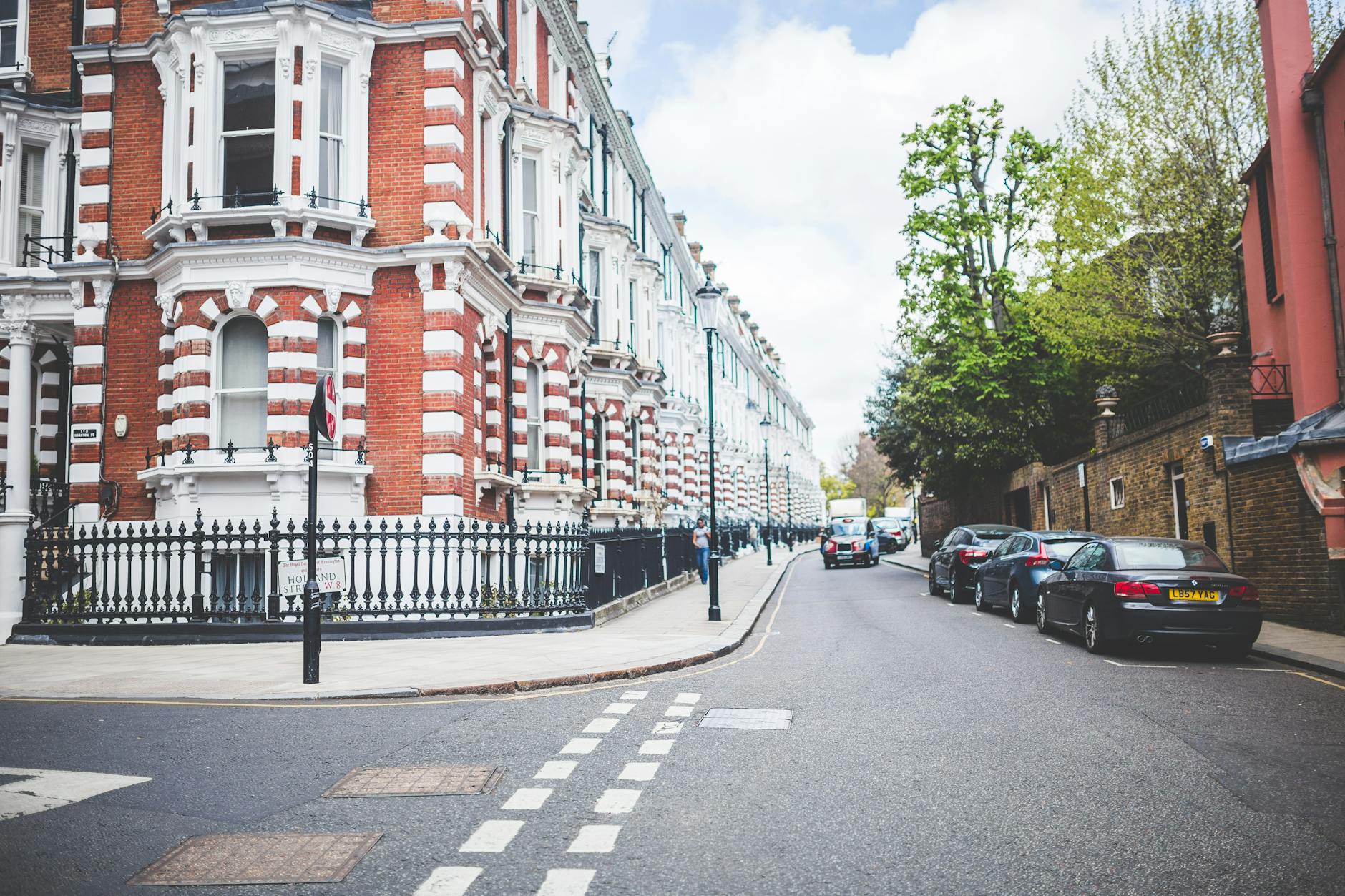 Stunning view of Victorian buildings on a city street corner with parked cars and lush trees.