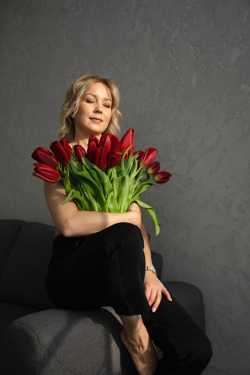 Studio Shot of a Young Woman Holding a Bunch of Red Tulips 