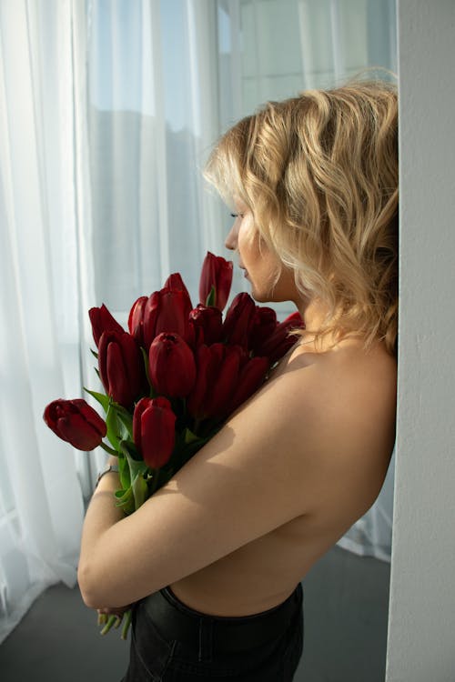 Blonde Woman Standing with Bunch of Red Tulips