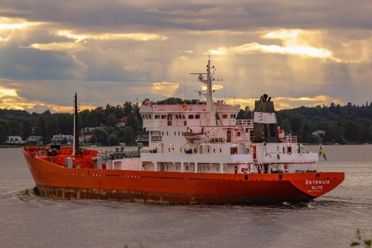 Large industrial ship navigating the waters near Sweden at sunset.