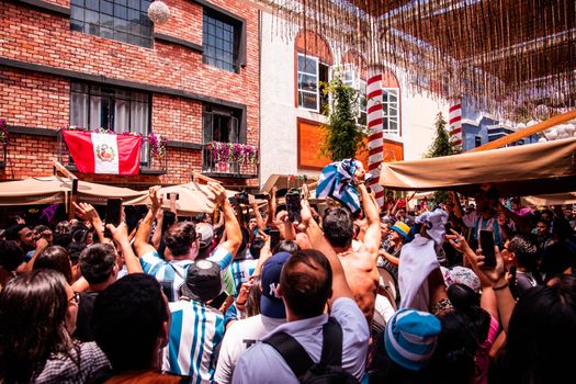 A lively crowd cheering with flags in Lima, Peru, showcasing cultural celebration and community spirit.