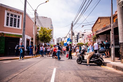 People celebrating on a street in Miraflores, Lima, with flags and festivities.