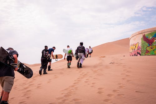 People with Sandboards on Desert