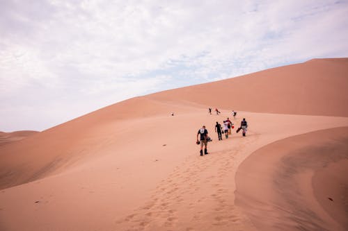 People Walking on Barren Desert Hill