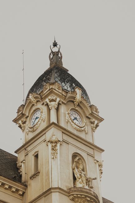 A classic clock tower with ornate details and sculptures under a muted sky.