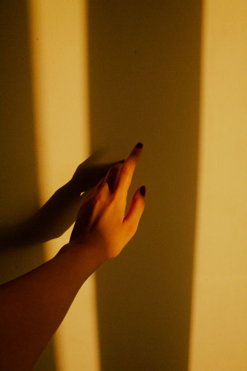 Free A hand casts a dramatic shadow on a sunlit wall, creating an artistic silhouette. Stock Photo