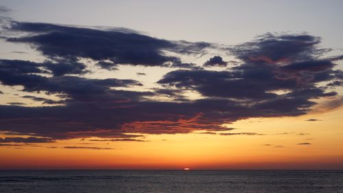 Free A breathtaking sunset with dramatic clouds over a calm ocean, capturing nature's beauty. Stock Photo