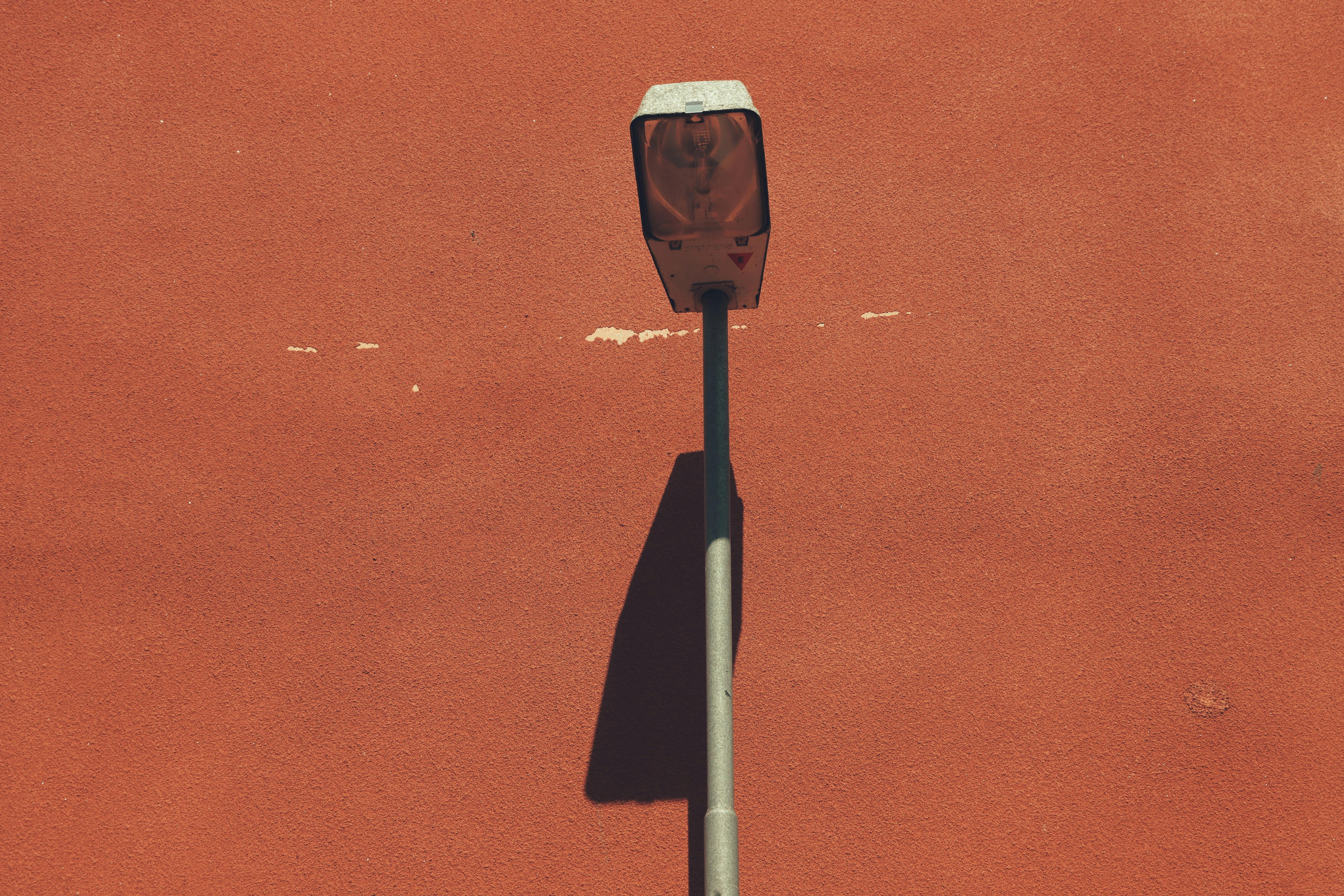 Free Close-up of a street lamp casting a shadow on a red wall in Jönköping, Sweden. Stock Photo