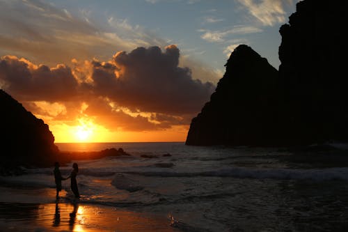 Free Holding Hands Couple Standing in Ocean at Sunset Stock Photo