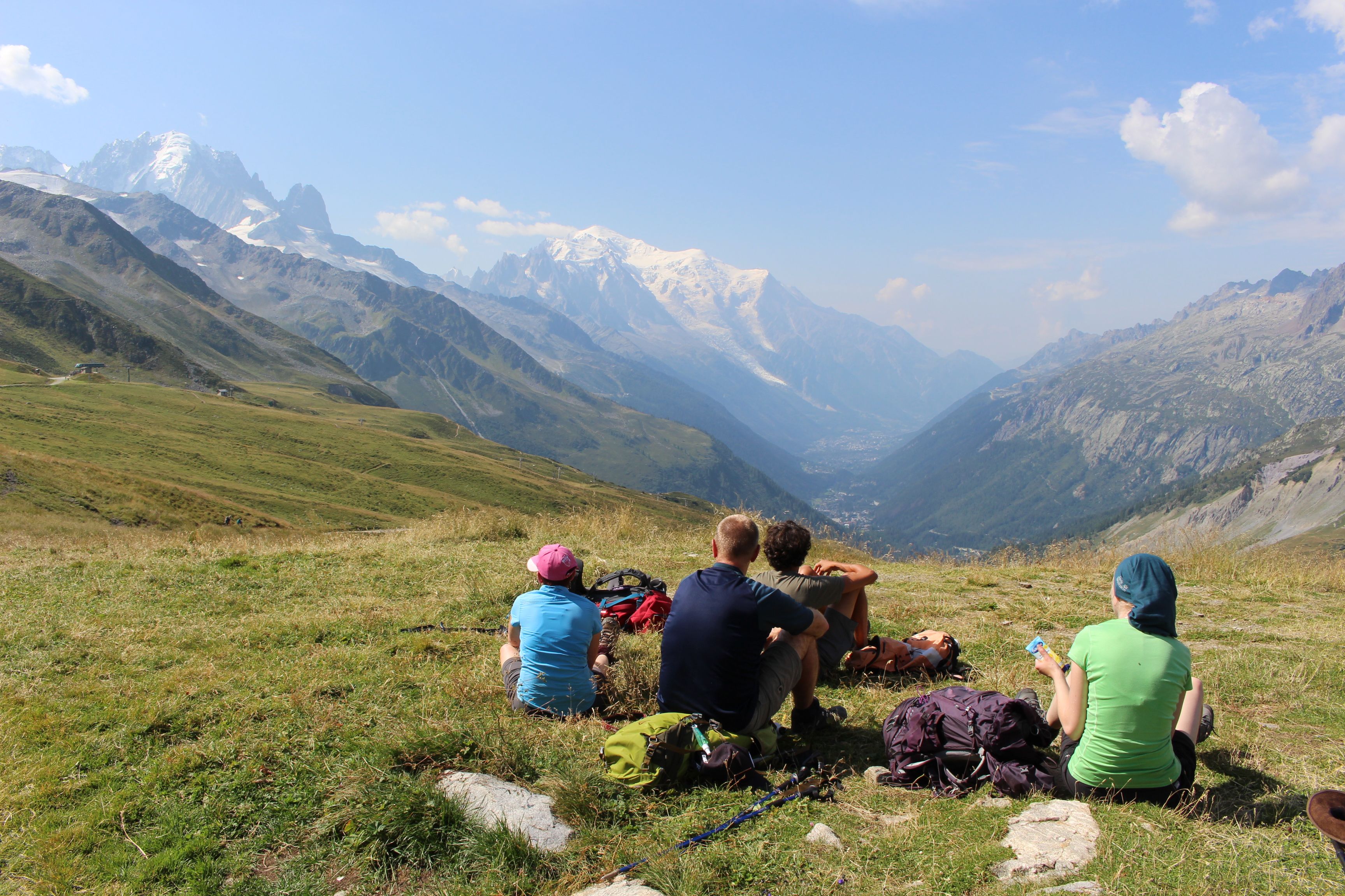 A group resting on the grass above an alpine valley