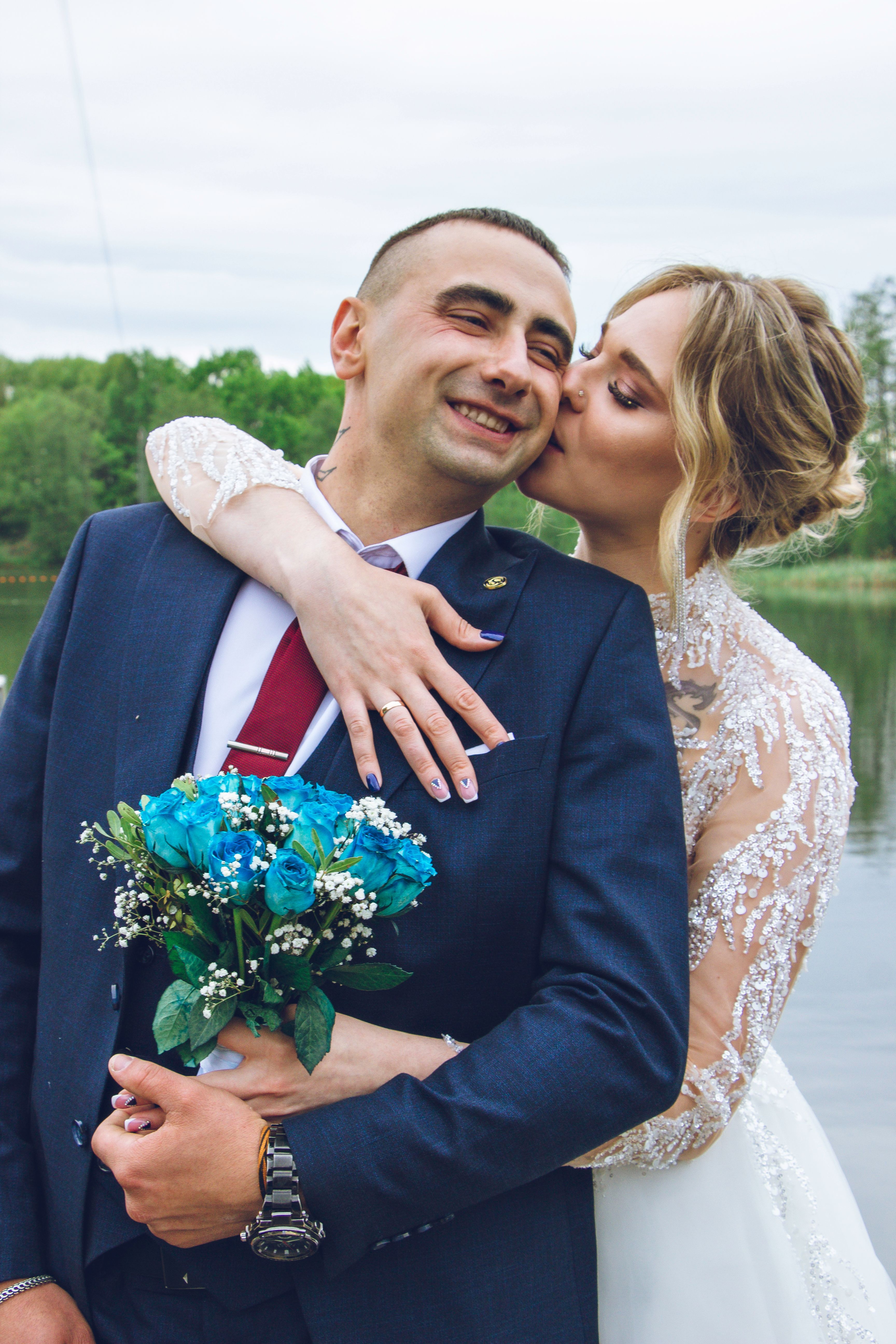 A bride and groom hugging by a picturesque lake, celebrating their wedding day.