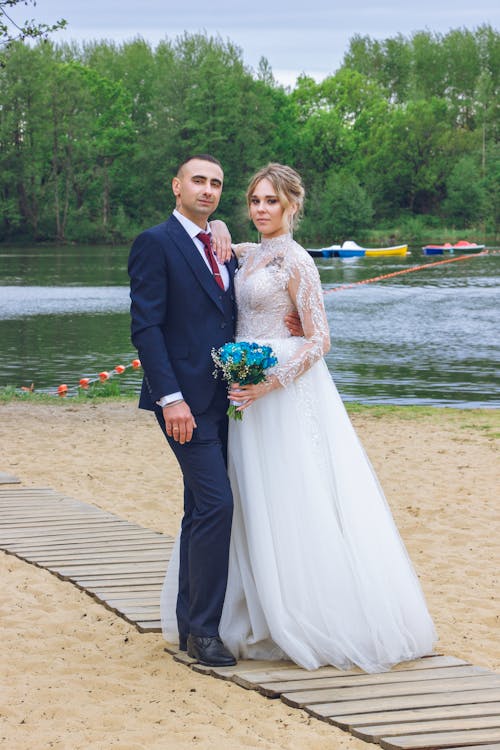 Newlyweds Posing Together on Wooden Footpath near Water