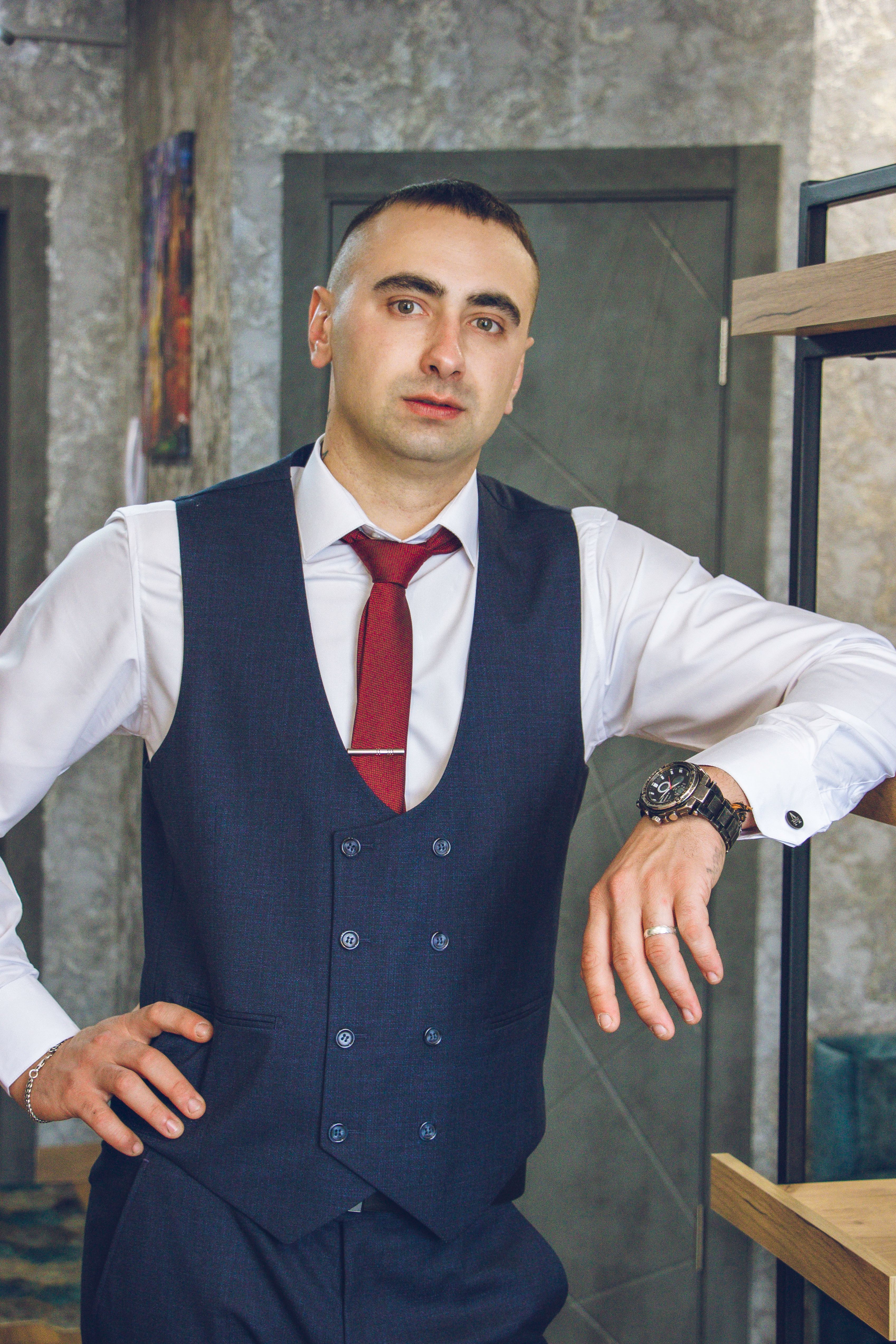 Stylish man in formal attire confidently posing indoors in a modern setting.