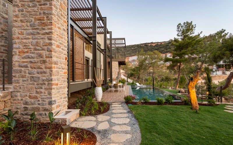 Landscaped garden with lawn, planting beds and pool beside a contemporary villa