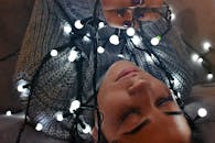 一位女子的室内肖像被发光的串灯环绕，传递出温暖与节日的氛围