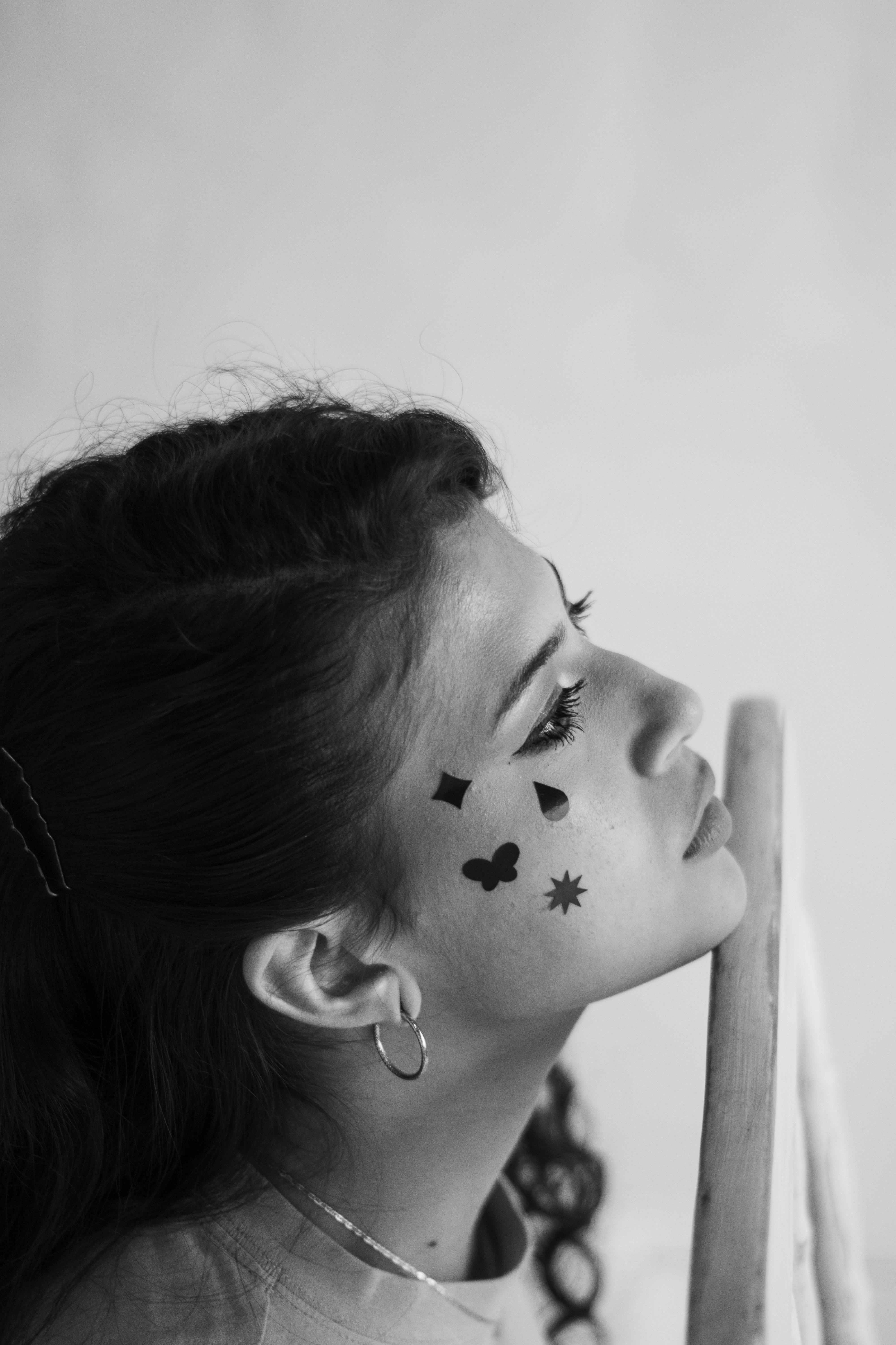Black and white profile portrait of a woman featuring artistic face art designs.